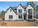 View of a two story home with gray trim, a black front door and yellow shrubbery at 3735 Tamiami Trl, Cumming, GA 30041