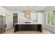 Bright kitchen featuring white cabinetry, stainless steel appliances, and a dark center island at 3735 Tamiami Trl, Cumming, GA 30041