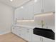 Laundry room featuring white cabinets, gold hardware, and a black farmhouse sink at 3735 Tamiami Trl, Cumming, GA 30041