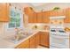 A bright kitchen featuring wood cabinetry and modern white appliances set beneath a sunlit window at 4034 Brockett Walk, Tucker, GA 30084