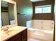 Bathroom featuring a single vanity, a large soaking tub, and a window for natural light at 997 Timbervale Ln, Lithonia, GA 30058