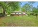 Well-manicured backyard with green grass, mature trees and the back of the house at 3800 Whitaker Ln, Lithia Springs, GA 30122
