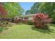 Landscaped front yard of a single-story home, featuring a brick facade, green lawn, and mature trees at 3800 Whitaker Ln, Lithia Springs, GA 30122