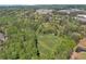 High aerial view displaying a lush, green landscape with open field, bounded by trees, a golf course, and nearby buildings at 1819 Yorkshire Dr, Woodstock, GA 30189