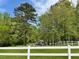 Scenic outdoor view of a lush, grassy field with a large tree and a barn, enclosed by a classic white fence at 1819 Yorkshire Dr, Woodstock, GA 30189