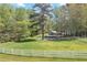 Picturesque view of a large, grassy field with a white fence, a barn, and mature trees creating a serene setting at 1819 Yorkshire Dr, Woodstock, GA 30189