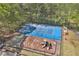 Aerial view of a blue tennis court and adjacent basketball court and playground, all surrounded by a tall fence at 1819 Yorkshire Dr, Woodstock, GA 30189