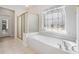 Elegant bathroom with a soaking tub, a shower with glass door, and decorative windows at 1330 Badingham Dr, Cumming, GA 30041