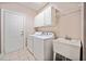 Laundry room with washer, dryer, sink, cabinets, white door and tile flooring at 1330 Badingham Dr, Cumming, GA 30041