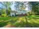 Green backyard with a wooden deck, surrounded by mature trees at 4166 Rue Saint Michel, Stone Mountain, GA 30083