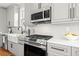 Close-up of kitchen featuring stainless steel range, microwave and farm sink with modern faucet at 106 Hogue St, Atlanta, GA 30312