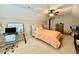 Bedroom features plush carpet, neutral walls, ceiling fan, desk, and bed with tan headboard and peach bedding at 3240 Letha Woods Sw Dr, Conyers, GA 30094