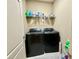 Laundry room featuring sleek black washer and dryer with ample shelving at 3240 Letha Woods Sw Dr, Conyers, GA 30094