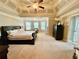 Expansive main bedroom with a tray ceiling, neutral carpet, a luxurious bed, and a large picture window at 3240 Letha Woods Sw Dr, Conyers, GA 30094