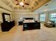 Spacious main bedroom featuring a tray ceiling, neutral carpet, a large bed, and a cozy sitting area at 3240 Letha Woods Sw Dr, Conyers, GA 30094