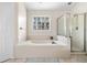 Bright bathroom with a tub, glass shower, and tile flooring at 3969 Bear Ridge Nw Pl, Kennesaw, GA 30144