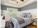 Cozy main bedroom featuring a tray ceiling, a large window, and a comfortable king-size bed at 6765 Creek View Ln, Cumming, GA 30041