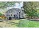 Rear exterior with an extensive lawn, tall windows, and an entertainment deck at 10355 Oxford Mill Cir, Johns Creek, GA 30022