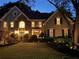 Inviting two-story home with stone accents and manicured lawn, beautifully illuminated at twilight at 10355 Oxford Mill Cir, Johns Creek, GA 30022