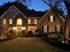 Elegant home exterior at dusk, with manicured lawn, landscape lighting, and stone accents enhancing curb appeal at 10355 Oxford Mill Cir, Johns Creek, GA 30022