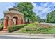 Community entrance featuring a beautiful brick gazebo surrounded by colorful flowers and lush landscaping at 10355 Oxford Mill Cir, Johns Creek, GA 30022