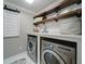 This functional laundry room features dual front-loading washer and dryer with dark wood shelving for storage and organization at 147 Johnston Farm Ln, Woodstock, GA 30188