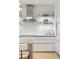 Bright and modern kitchen with white backsplash, stainless steel hood, floating shelves and white cabinets at 3107 Peachtree Ne Rd # 1403, Atlanta, GA 30305