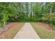 A concrete walking path leads through a serene wooded area with lush green foliage at 3638 Silvery Way, Powder Springs, GA 30127
