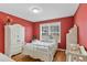 Cozy bedroom with red walls, hardwood floors, and white furnishings, bathed in natural light at 104 Lumby Ln, Stockbridge, GA 30281