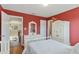 Cozy bedroom with red walls, hardwood floors, and white furnishings, bathed in natural light at 104 Lumby Ln, Stockbridge, GA 30281