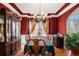 Formal dining room featuring red walls, hardwood floors, tray ceilings, and elegant chandelier at 104 Lumby Ln, Stockbridge, GA 30281