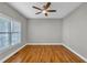 Cozy bedroom featuring hardwood floors, a ceiling fan, and natural light from a large window at 3634 Lost Oak Dr, Buford, GA 30519