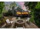 Serene backyard featuring a stone fire pit with Adirondack chairs, lush greenery and beautiful landscaping at 540 Cambridge Way, Atlanta, GA 30328