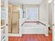 Bright bathroom showcases a shower, a luxurious soaking tub and red-tiled floors with a tiled-accented backsplash at 210 Chandler Ct, Sugar Hill, GA 30518
