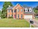 Charming two-story brick home featuring a well-manicured lawn, a red front door, and an attached two-car garage at 210 Chandler Ct, Sugar Hill, GA 30518
