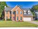 Stately brick home with a manicured front lawn, red front door, dormer windows, and two-car garage at 210 Chandler Ct, Sugar Hill, GA 30518