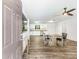 Open-concept living space with modern wood floors, ceiling fan, and kitchen with white cabinets in the background at 8405 Military Way, Douglasville, GA 30134