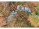Bird's-eye view of a creek winding through a dense forest with varying shades of autumn leaves at 918 Guinevere Way, Lilburn, GA 30047
