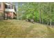 Lush green lawn and tall trees surround the home in this backyard view at 918 Guinevere Way, Lilburn, GA 30047