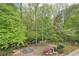 Expansive backyard view featuring mature trees, a fire pit, and colorful flowering bushes at 918 Guinevere Way, Lilburn, GA 30047