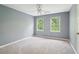 A blue bedroom with windows overlooking greenery, light carpet flooring, and a fan overhead at 918 Guinevere Way, Lilburn, GA 30047