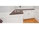 Wet bar with white cabinets, a brown countertop, stainless steel sink, and wood flooring at 918 Guinevere Way, Lilburn, GA 30047