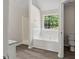 Bright bathroom features a tub, separate shower, and stylish wood-look flooring at 1389 Shadow Creek Ave, Hampton, GA 30228