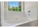 Inviting bathtub features tiled backsplash and a large window to the backyard at 1389 Shadow Creek Ave, Hampton, GA 30228
