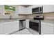 Modern kitchen featuring stainless steel appliances, granite countertops, and white cabinets at 1389 Shadow Creek Ave, Hampton, GA 30228