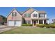 Charming two-story brick home featuring a well-manicured lawn, covered porch, and a two-car garage at 209 Crestmont Way, Canton, GA 30114