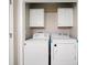 Bright laundry room featuring a washer, dryer, and convenient overhead cabinets for ample storage at 200 High Creek Dr, Roswell, GA 30076
