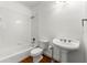 Clean, white bathroom features a classic pedestal sink and tiled shower-tub combination at 562 Grassmeade Way, Snellville, GA 30078