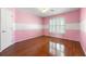 Pink and white striped bedroom with hardwood floors, ceiling fan, and window with white shuttered blinds at 562 Grassmeade Way, Snellville, GA 30078