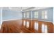 Spacious bedroom with hardwood floors, blue walls, white trim, a tray ceiling, and many shuttered windows at 562 Grassmeade Way, Snellville, GA 30078